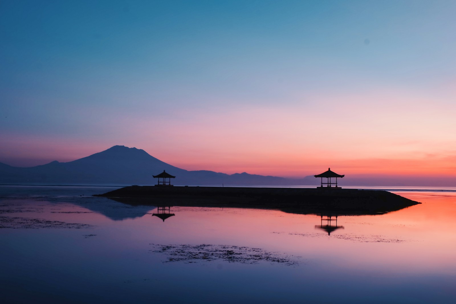 A sunset view of a small island in the middle of a body of water